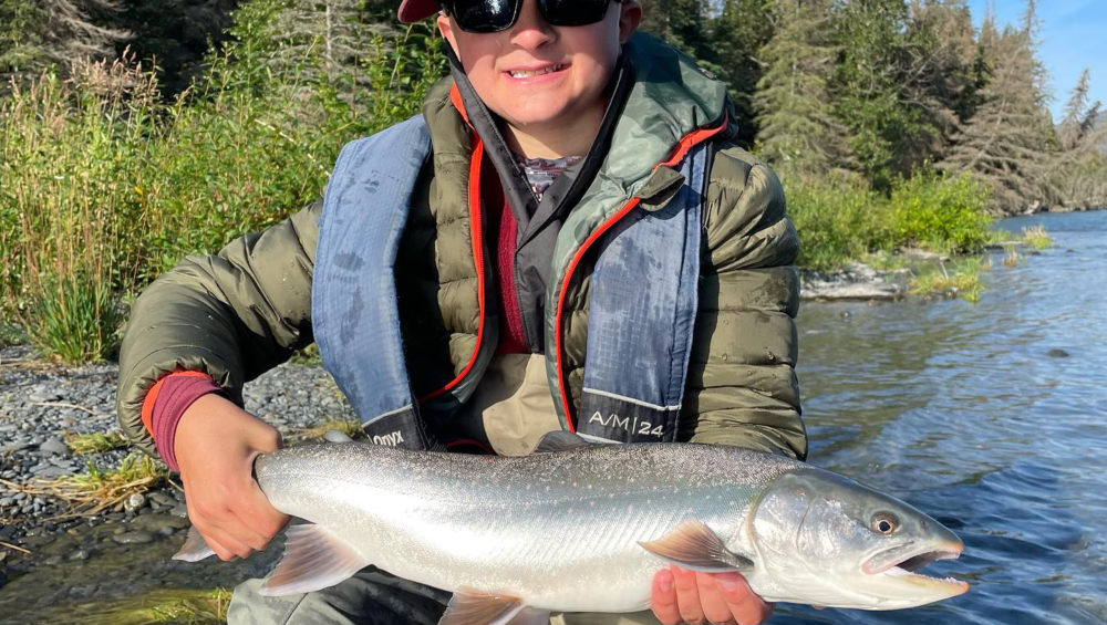 an angler smiling as he poses with Dolly Varden char on the Kenai River