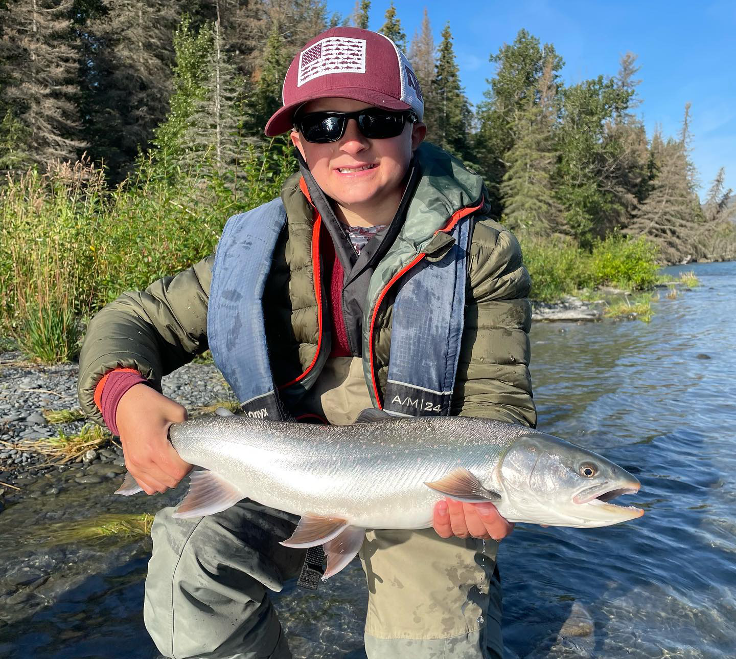 an angler smiling as he poses with Dolly Varden char on the Kenai River