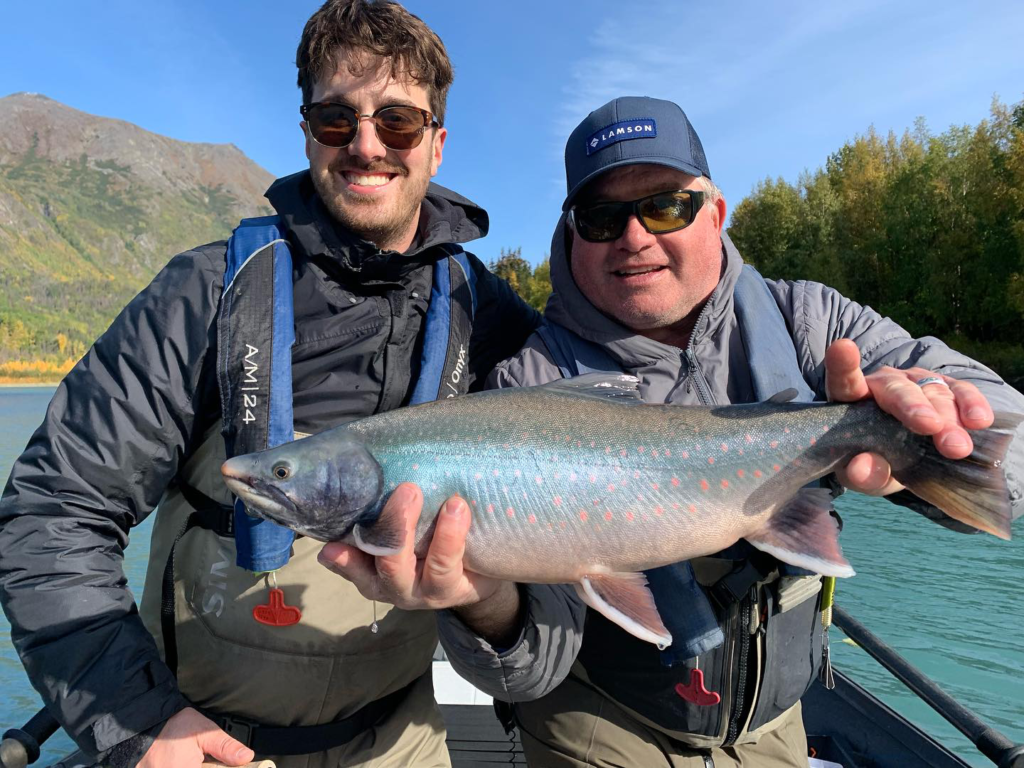 fishing guide Jason Lesmeister and an angler smiling as they show off Dolly Varden char during their Kenai River fishing trip