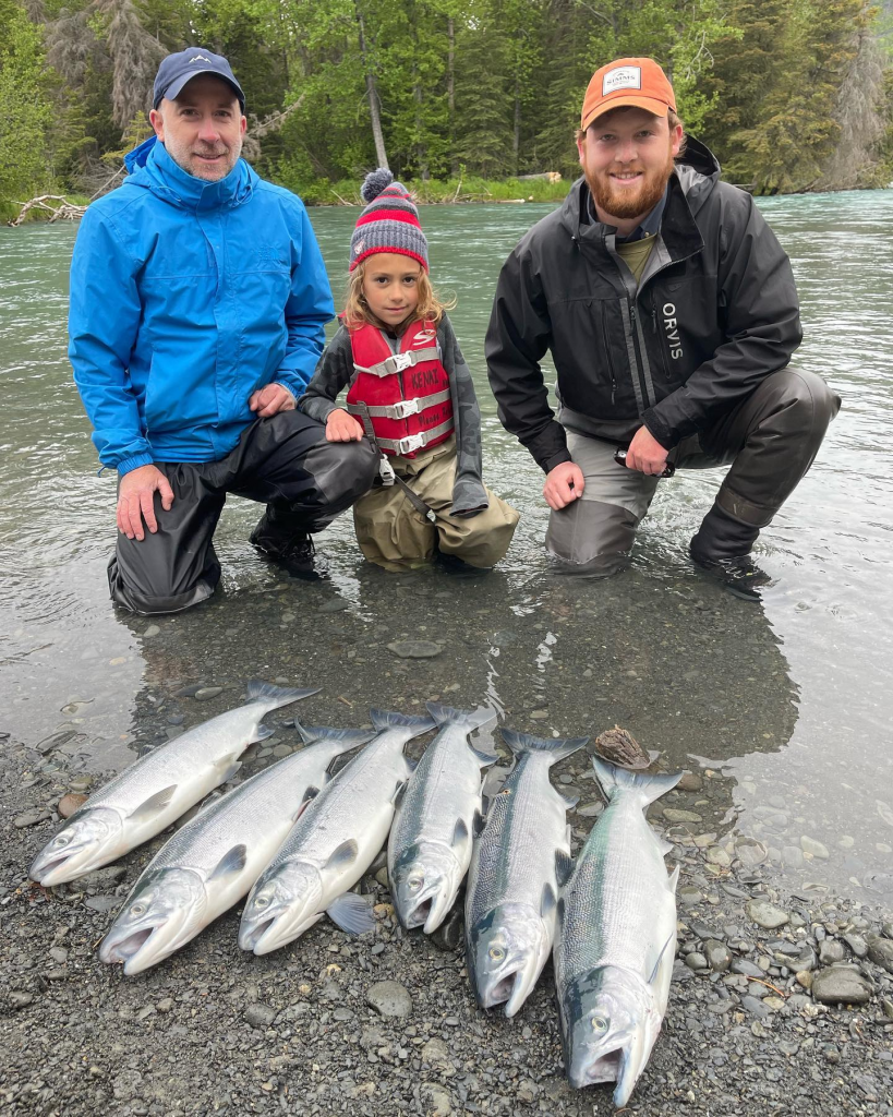 a child and anglers posing next to sockeye salmon