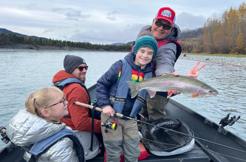 a fishing guide and child smiling as they proudly hold a big fish on the Kenai River