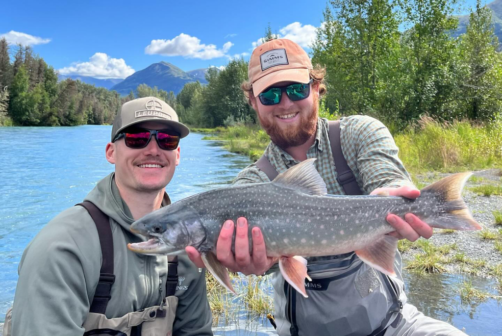 Against the backdrop of the Kenai River's scenic beauty, people hold up fish they've caught, illustrating the principles of sustainable fishing