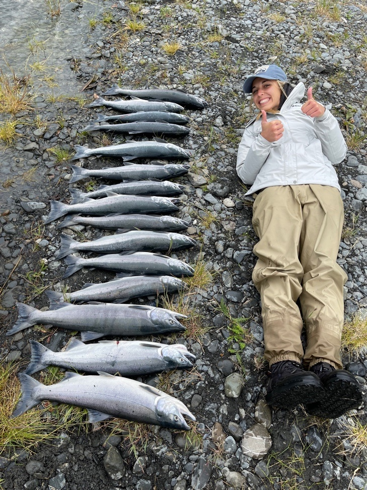 A woman is posing with the fish she caught