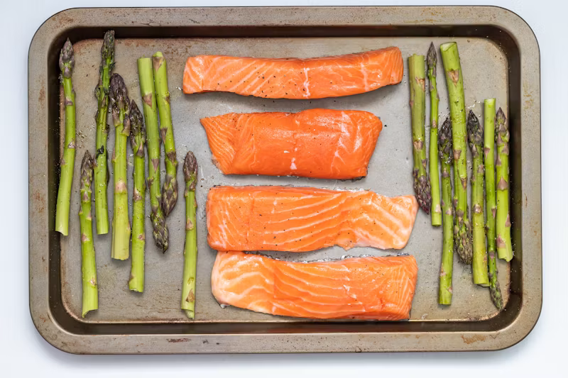 Salmon fillets on a baking tray with asparagus.