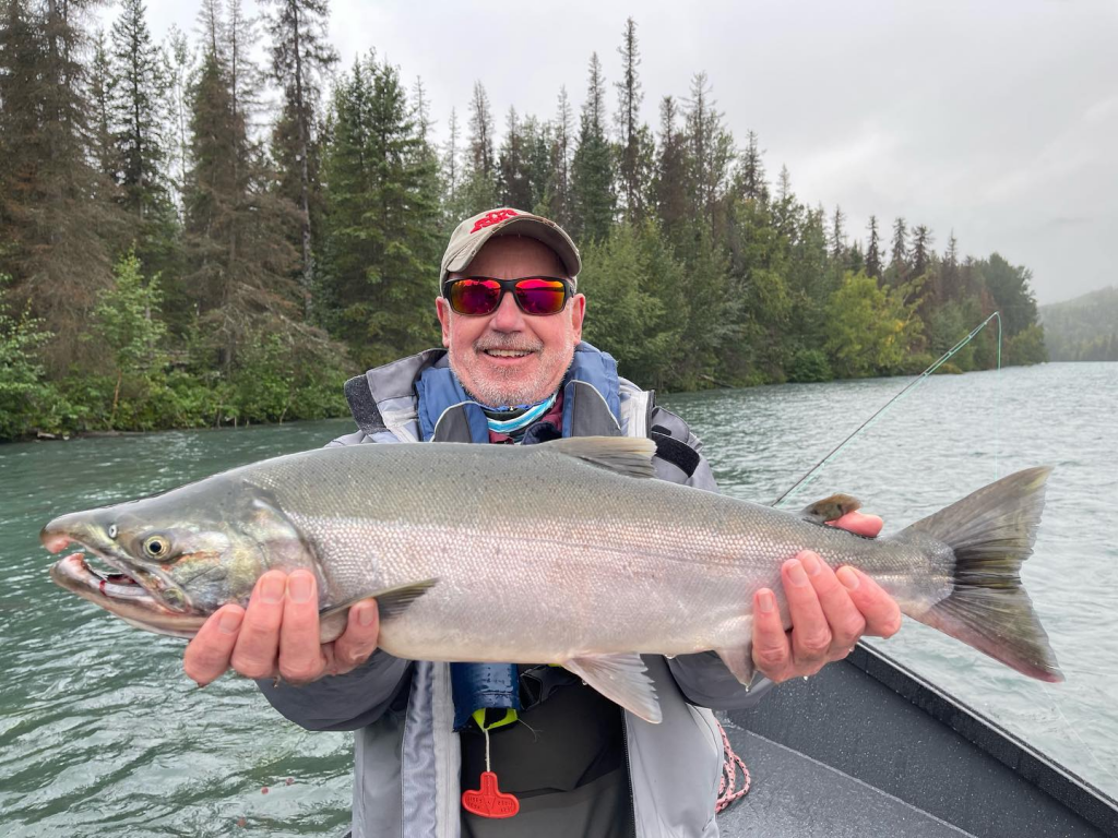 An angler holding a big silver salmon from the Kenai River in Cooper Landing.