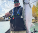 An angler holding a big silver salmon on a drift boat on the Kenai River.