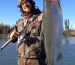 An angler proudly holding a silver salmon by the Kenai River.