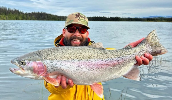 An angler excitedly holding a rainbow trout caught on the Kenai River.